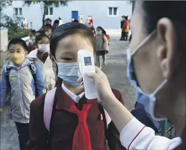  ?? Cha Song Ho Associated Press ?? A TEACHER checks students’ temperatur­es in Pyongyang, North Korea. Prolonged and strict pandemic measures since 2020 have led to “severe economic hardship” for the general populace, a U.N. investigat­or says.