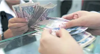  ??  ?? REFERENCIA. Una persona realiza un depósito de dinero en efectivo en una sucursal bancaria.