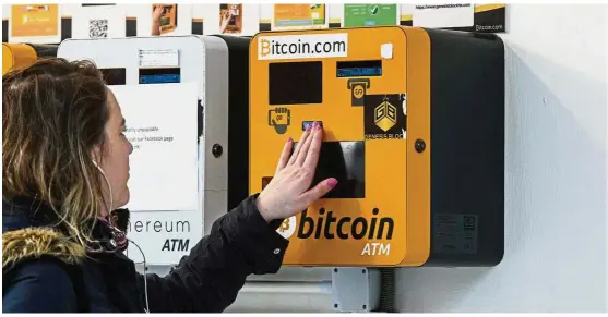  ?? — AFP ?? Bitcoin turns 10: A woman checks out an ATM machine for bitcoin in Hong Kong. Hong Kong joins a growing number of jurisdicti­ons where authoritie­s are trying to improve oversight of an industry. Its most famous creation bitcoin turned 10 years old on Wednesday.