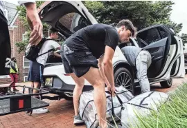  ?? BENJAMIN ?? First-year student Matt Barreira, at left, unpacks the car trunk and is assisted by his family during his move to campus at the University of Delaware's South Academy Hall in Newark on Aug. 25, 2023. Newark hopes to levy a per-student tax on universiti­es and is also seeking authority to tax rental revenues.