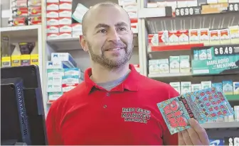  ?? STAFF PHOTO BY NANCY LANE ?? ‘HE DESERVES IT’: Sam Safa, owner of Reeds Ferry Market in Merrimack, N.H., who sold the winning $559 million Powerball ticket, sells more lottery tickets yesterday.