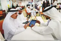  ?? Virendra Saklani/Gulf News ?? Esmail Abdul Rahim Mohammad (left), head of Al Twar ■ centre, encouragin­g visitors to use online services yesterday.