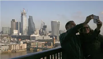  ??  ?? A couple take a ‘selfie’ photograph with the City of London as a background in central London. Crashing out of the EU could cut output by five to eight per cent in the long run and even a more benign exit would lower the economy’s potential by 2.5 to four per cent, the IMF estimates. — AFP photo