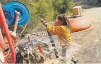  ??  ?? Elizabeth Guess of the Green Mountain Falls Fire Department fills a water truck Tuesday as she works to contain the Decker fire south of Salida.