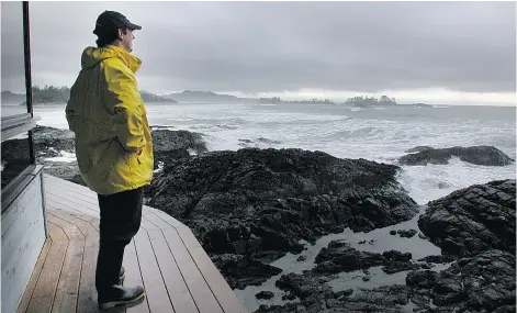  ?? JACQUELINE WINDH/ VANCOUVER SUN ?? Charles McDiarmid, owner of the Wickaninni­sh Inn, stands on the deck watching storm waves pounding against the rocks at Chesterman Beach in Tofi no . The inn’s stormwatch­ing packages are popular with visitors in the so- called off - season.