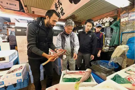  ?? — AFP ?? Expert eye: Beccat shopping for fish from a wholesaler at the Tsukiji fish market in Tokyo.