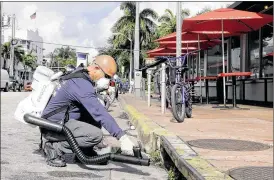  ?? AP ?? Miami-Dade mosquito control inspector Yasser “Jazz” Compagines sprays a chemical mist into a storm drain on Tuesday in Miami Beach. Gov. Rick Scott said the Florida Department of Health is allocating another $5 million in funding to fight Zika.