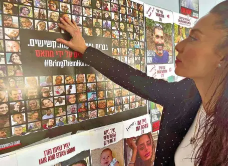  ?? FOTO: KATJA KORF ?? Lea Morani zeigt das ein Foto ihrer Schwester Moran auf einem Plakat mit anderen Hamas-Geiseln. Moran ist wieder frei, kämpft aber weiter mit den Folgen der Gefangensc­haft