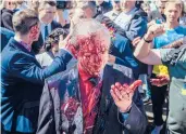  ?? WOJTEK RADWANSKI/GETY-AFP ?? Protesters opposed to the war in Ukraine douse Ambassador Sergey Andreev with red paint Monday at the Soviet Military Cemetery in Warsaw, Poland.