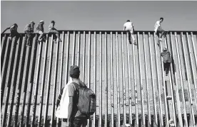  ?? FOTOS AFP ?? Algunos migrantes escalan el muro que divide Tijuana con San Diego.