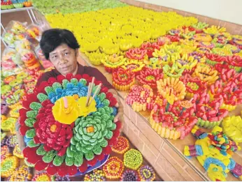  ?? APICHIT JINAKUL ?? A worker at Wat Thanyaphol in tambon Lam Luk Ka of Pathum Thani’s Lam Luk Ka district shows off a krathong made of bread that will be sold to Loy Krathong revellers tonight at the temple.