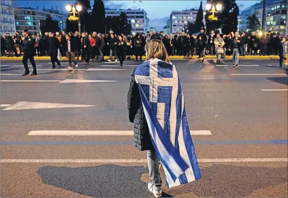  ?? LOUISA GOULIAMAKI / AFP ?? Una mujer frente al Parlamento griego en Atenas muestra su apoyo a la política de Syriza contra la austeridad y a favor del crecimient­o