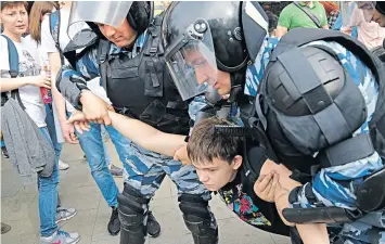  ??  ?? A young protester is handled by riot police at a demonstrat­ion in Moscow. The opposition leader was held as he left home for a rally