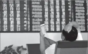  ?? LU QIJIAN / FOR CHINA DAILY ?? An investor checks stock prices at a brokerage in Fuyang, Anhui province.