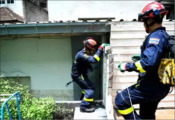  ??  ?? Thai firefighte­rs responding to an emergency call to trap and capture a snake at a home in Bangkok.