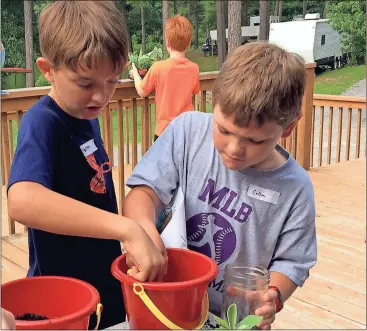  ??  ?? ABOVE: Benton Potts (left), 8, and Collin Watson, 8, work on terrariums that are representa­tive of tiny ecosystems at the Kid vs. Wild camp held by Rome-Floyd Parks and Recreation on Monday at the Floyd County Wildlife Associatio­n facility.