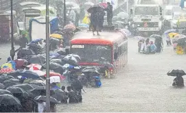  ??  ?? Die Überflutun­gen haben nun auch Mumbai erreicht. Viele versuchten mittels Regenschir­men zumindest am Kopf trocken zu bleiben.