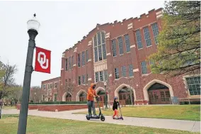  ?? [THE OKLAHOMAN ARCHIVES] ?? Two people ride scooters past McCasland Field House on the University of Oklahoma campus in March. OU and OSU are working to help internatio­nal students whose presence in the U.S. could be threatened by federal rules.