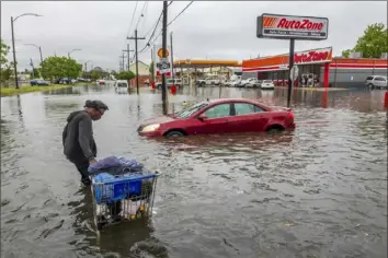  ?? Chris Granger/The Times-Picayune/The New Orleans Advocate via AP ?? People carry their belongings down a flooded Broad Street in New Orleans, during a severe rainstorm on Wednesday.