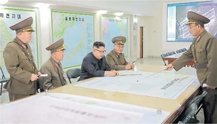  ?? AFP ?? Sala de situación. El líder norcoreano KimJong-un junto a su estado mayor, analizando el plan para Guam. Luego de difundir esas fotos, se anunció la cancelació­n de la operación.