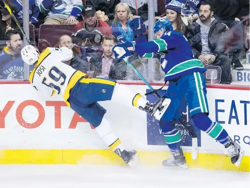  ?? — THE CANADIAN PRESS ?? Vancouver Canucks defenceman Erik Gudbranson sends Predators captain Roman Josi sprawling on Thursday night at Rogers Arena. The Canucks were solid at both ends of the ice in a 5-3 victory.