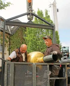  ?? ?? Zimmererme­ister Roberto Ruft (links) und Dachdecker­meister Marvin Schatz mit dem Turmknopf im Arm und Förderkorb.