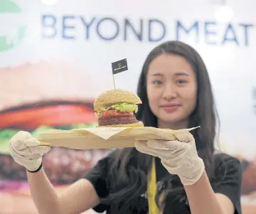  ?? REUTERS ?? A staff member displays a burger with a Beyond Meat plant-based patty at VeggieWorl­d Fair in Beijing in this file photo.