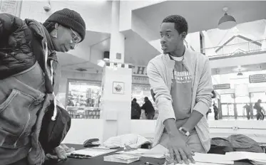  ?? KARL MERTON FERRON/BALTIMORE SUN ?? Jane Nesbitt, of West Baltimore, listens to Eean Logan, director of civic culture and youth programs with No Boundaries Coalition, Nov. 14 at Lexington Market as a group of community organizati­ons conduct a survey to track resident priorities.