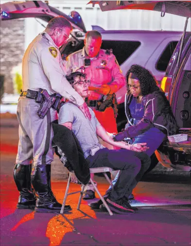  ?? ?? Above: Metro officer Anthony Manginelli, left, helps calm impaired driving suspect Mike Soto as phlebotomi­st Ashley Webber-gamboa with Sunrise Pathology Services, right, draws a blood sample during a DUI Blitz on April 16 in Las Vegas.