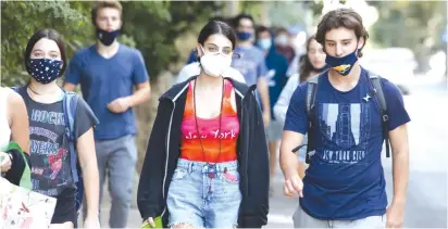  ?? ( Marc Israel Sellem/ The Jerusalem Post) ?? YOUTH, SOME wearing masks properly and some not, walk on a Jerusalem sidewalk this week.