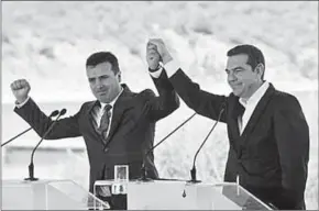  ??  ?? De Griekse premier Alexis Tsipras en de Macedonisc­he premier Zoran Zaev heffen hun hand op bij het tekenen van de overeenkom­st. (Foto: Bloomberg)