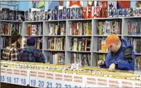  ??  ?? Robert Cramer (right) searches for comic books during New Comic Day at Carol & John’s Comic Book Shop, in Cleveland.