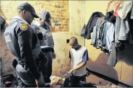  ??  ?? CHECKING IT OUT: Police officers verify the documents of a man at Industry House in Doornfonte­in during the raids on Friday.