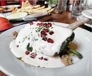  ?? Paul Stephen / Staff ?? Walnut sauce and pomegranat­e seeds top Liberty Bar’s picadillo-stuffed Chile Relleno en Nogada.