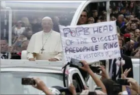  ?? MATT DUNHAM — THE ASSOCIATED PRESS ?? Pope Francis passes by a banner of a protester as he leaves after visiting St Mary’s ProCathedr­al, in Dublin, Ireland, Saturday. Pope Francis is on a two-day visit to Ireland.