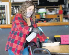  ??  ?? Stacey Shay, bartender at Moods Pub, wipes down a table with disinfecta­nt on Thursday.