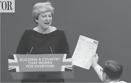  ?? PAUL ELLIS / AGENCE FRANCE-PRESSE / GETTY IMAGES ?? Protester/comedian Simon Brodkin gives a mock dismissal form to British Prime Minister Theresa May in Manchester on Wednesday.