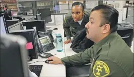  ??  ?? CUSTODY ASSISTANTS Alexis Herbert, left, and Victor Gamont review case files at the jail as detained inmates are processed within the system.