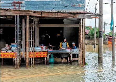  ?? ?? Business as usual: Life goes on in rantau Panjang, Kelantan, despite the floods. — Bernama