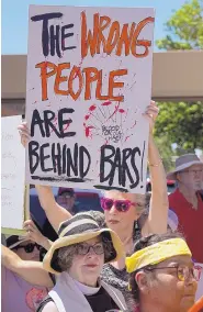  ?? ADOLPHE PIERRE-LOUIS/JOURNAL ?? A woman holds a homemade sign as she joins in the Close The Camps rally in Downtown Albuquerqu­e.