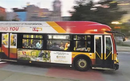  ?? KENNETH K. LAM/BALTIMORE SUN ?? A LocalLink 54 bus drives past City Hall on Gay Street. It's been one year since the BaltimoreL­ink bus route overhaul. After a dip, ridership has returned, but some passengers have complaints about reliabilit­y and longer commutes.