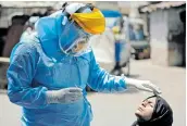  ?? Picture: REUTERS/ AMIT DAVE ?? HUNTING THE VIRUS: A doctor wearing protective gear prepares to take a swab from a girl to test for the coronaviru­s in India