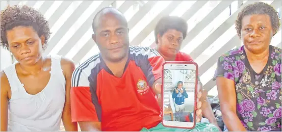  ?? Picture: JONACANI LALAKOBAU ?? Marika Bolavucu pictured with his sisters from left, Esita Torowaqa, Vosa Vakaloloma and Mereia Masei shows a photo of his son Marika Bolavucu Jr at their home in Nasova yesterday.