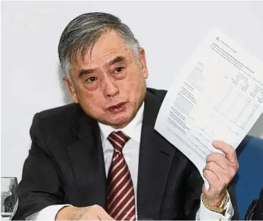  ??  ?? Good results: Tan holding up the company’s financial results at a press conference after the company AGM.