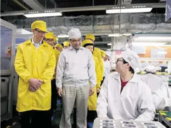  ?? KEYSTONE ?? Apple-CEO Tim Cook (l.) bei einem Besuch im Jahr 2012 in einer der iPhone-Fabriken von Foxconn.