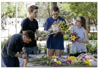  ?? RALPH BARRERA / AMERICAN-STATESMAN ?? From left, University of Texas students Kiyahn Navissi, Ben Friedman, Katherine Harclerode and Montana Moore, all members of the Undergradu­ate Business Council, place bouquets on picnic tables Tuesday at the Gregory Gym plaza, site of Monday’s fatal...