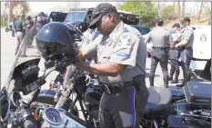  ?? Dave Collins / Associated Press file photo ?? Connecticu­t Trooper Walter Greene straps his helmet onto his motorcycle in Windsor in May 2015.