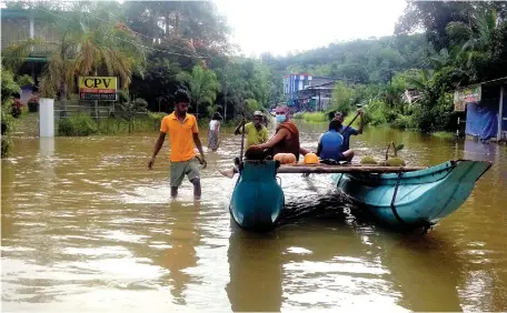  ??  ?? As the Matugama-Kalawana Road in the Kalutara district came under water, volunteers are seen taking the affected people to safety. Below: Earthslip in Agalawatte. Pic by Bandu Thambawita