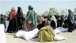  ?? /ALI KHARA/REUTERS ?? Afghan women wait to receive sacks of rice as part of humanitari­an aid sent by China.