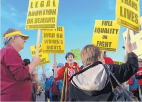  ?? GREG SORBER/JOURNAL ?? Bob Kuning, left, and Gerri Warner, center, both of Albuquerqu­e, hold signs during Wednesday’s march and rally on Internatio­nal Women’s Day at the University of New Mexico.